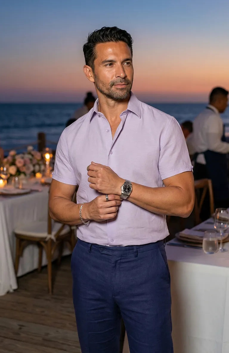 Man adjusting his Beckford Men’s Linen Shirt in Violet  at an outdoor event with tables and people in the background
