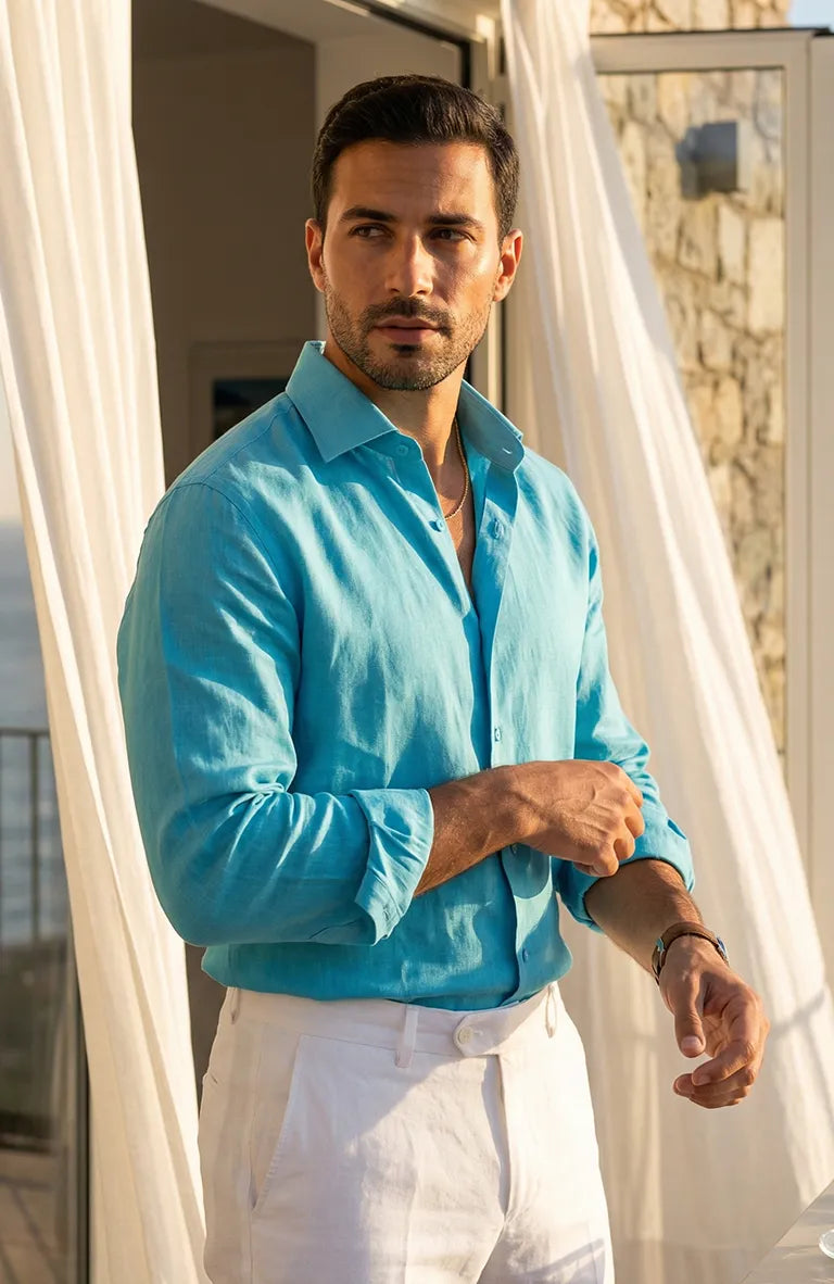 Man wearing a lBradford Italian Linen Shirt in Malibu and white pants standing in front of a stone wall.